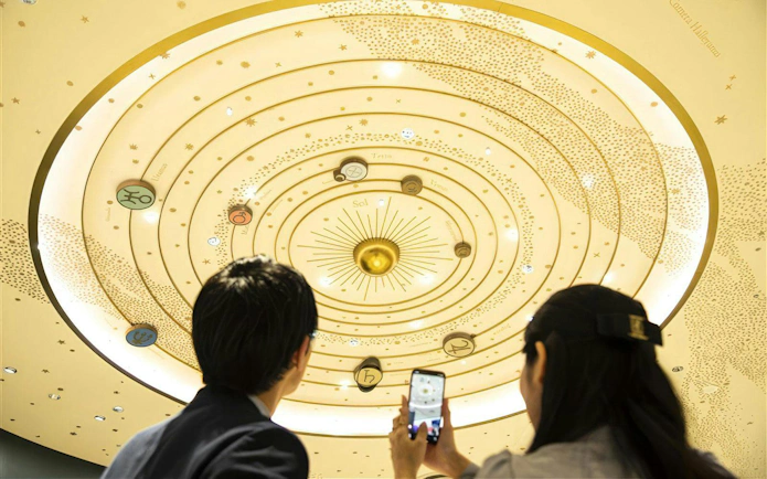 Visitors observing solar system display at Konica Minolta Planetaria TOKYO Ginza.