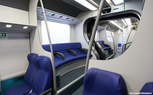 Interior of a train with blue seats, part of the Fiumicino Airport to Rome Termini route.
