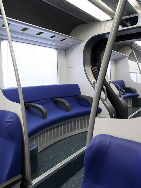 Interior of a train with blue seats, part of the Fiumicino Airport to Rome Termini route.