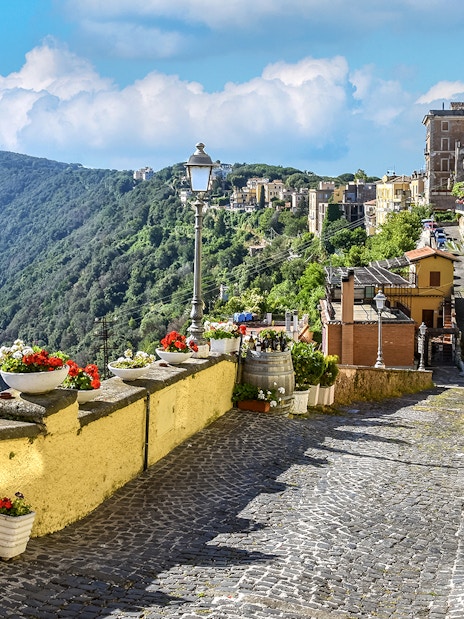 Cobblestone path with flowers overlooking Lake Albano near Castel Gandolfo, Italy.