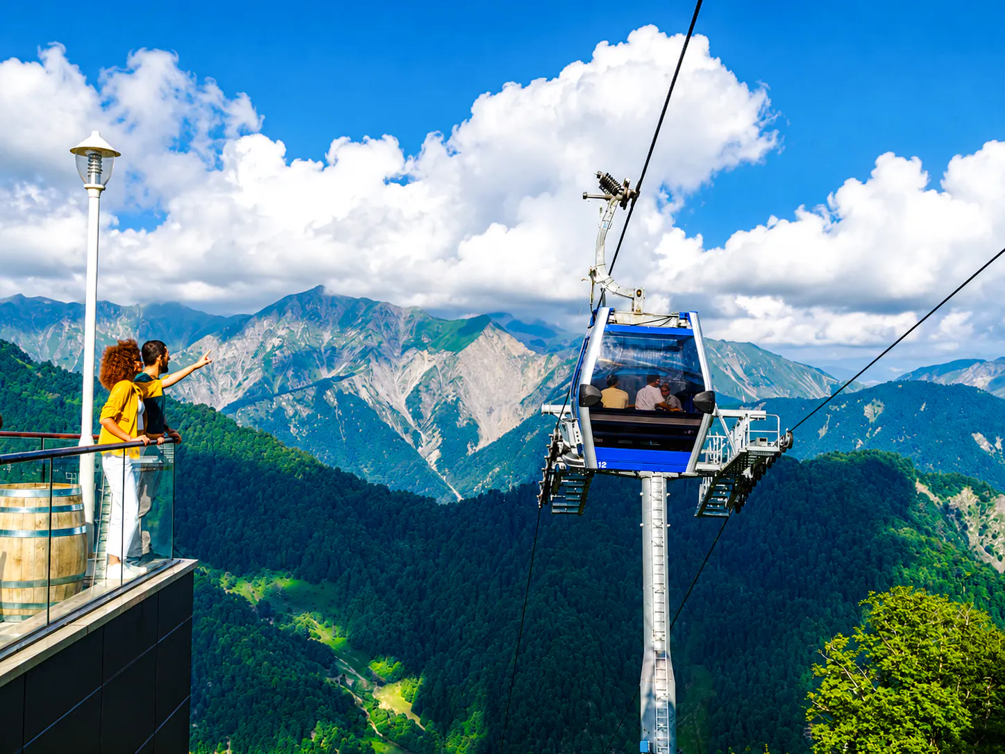 Cable car ascending over lush mountains in Gabala, Azerbaijan, with tourists enjoying the view.
