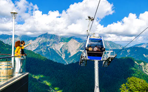 Cable car ascending over lush mountains in Gabala, Azerbaijan, with tourists enjoying the view.