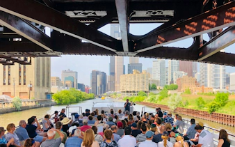Chicago River cruise with tourists viewing city skyline and architecture.