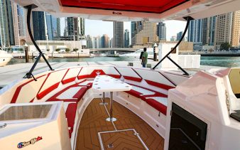 Boat interior with red seating at Dubai Marina, skyscrapers in the background, for parasailing tour.