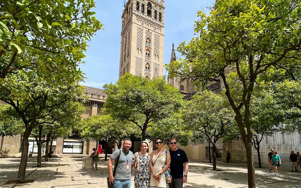 Visitors in courtyard with view of Giralda Tower, Seville, during guided tour.