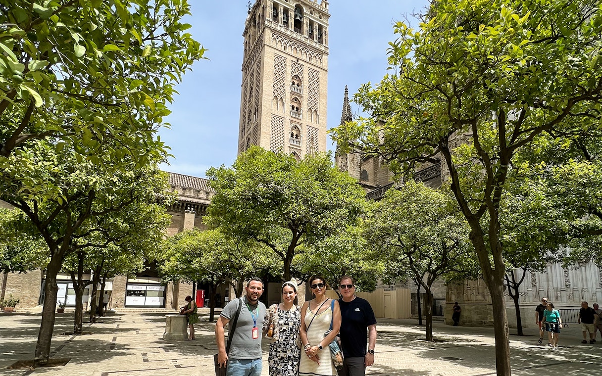 Visitors in courtyard with view of Giralda Tower, Seville, during guided tour.