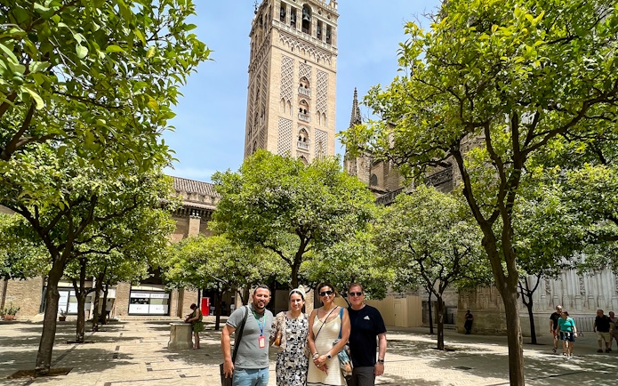 Visitors in courtyard with view of Giralda Tower, Seville, during guided tour.