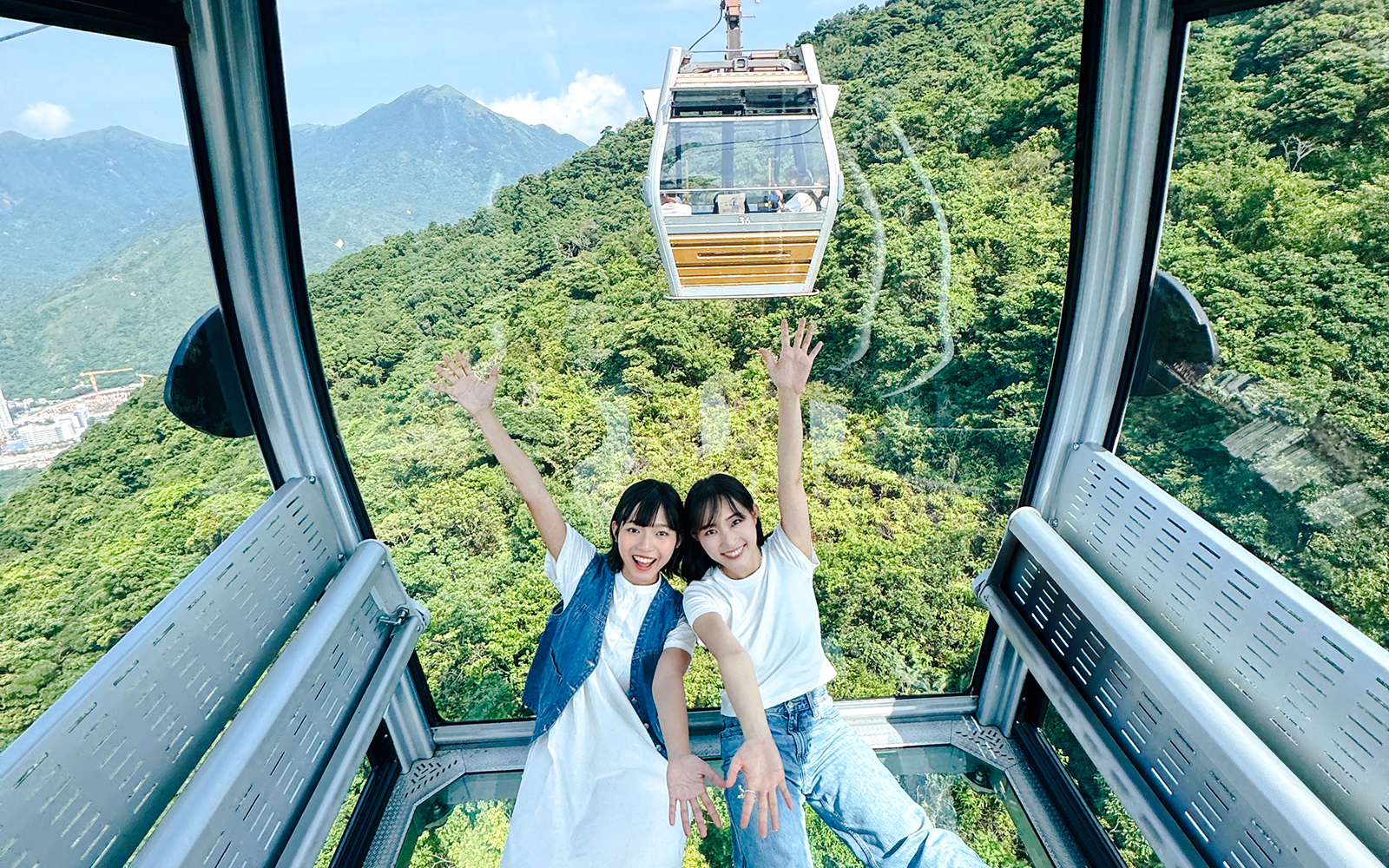 Tourists enjoying view inside cable car on Lantau Island Hop-on Hop-off Bus Tour.