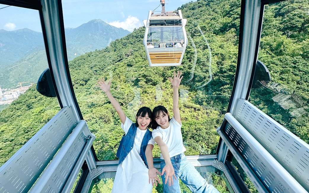 Tourists enjoying view inside cable car on Lantau Island Hop-on Hop-off Bus Tour.