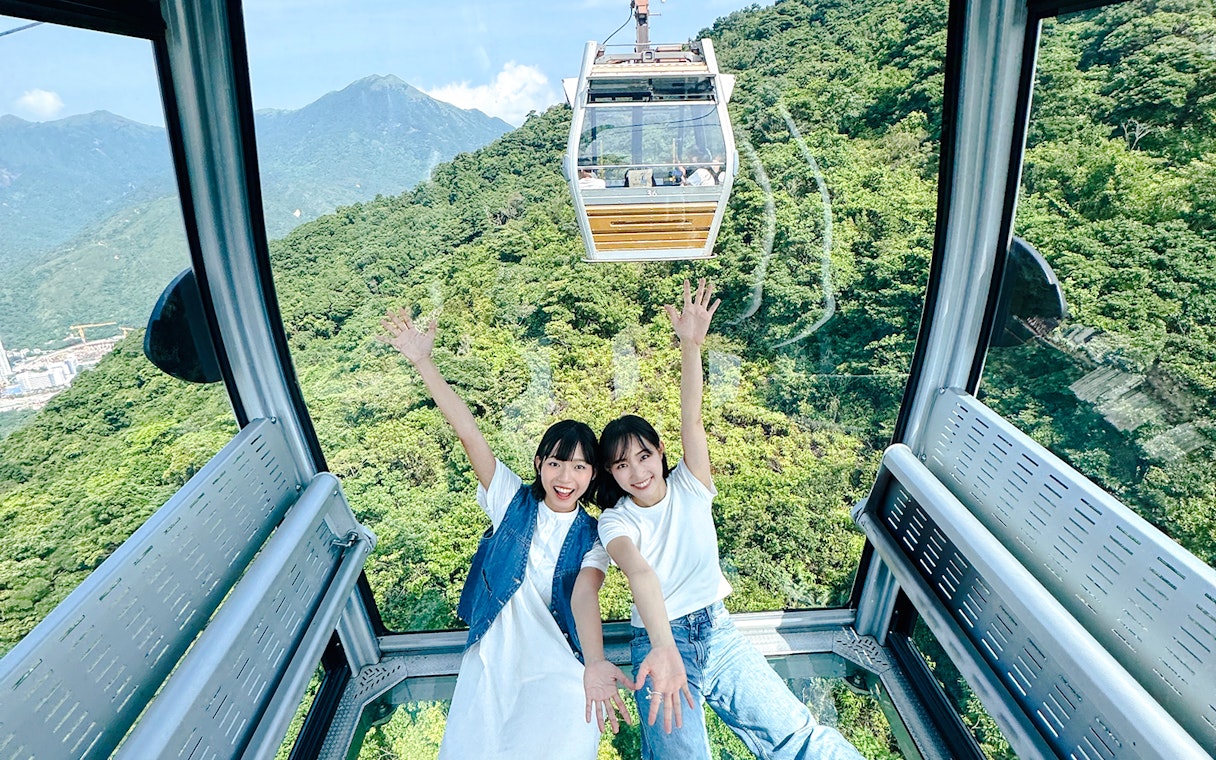 Tourists enjoying view inside cable car on Lantau Island Hop-on Hop-off Bus Tour.