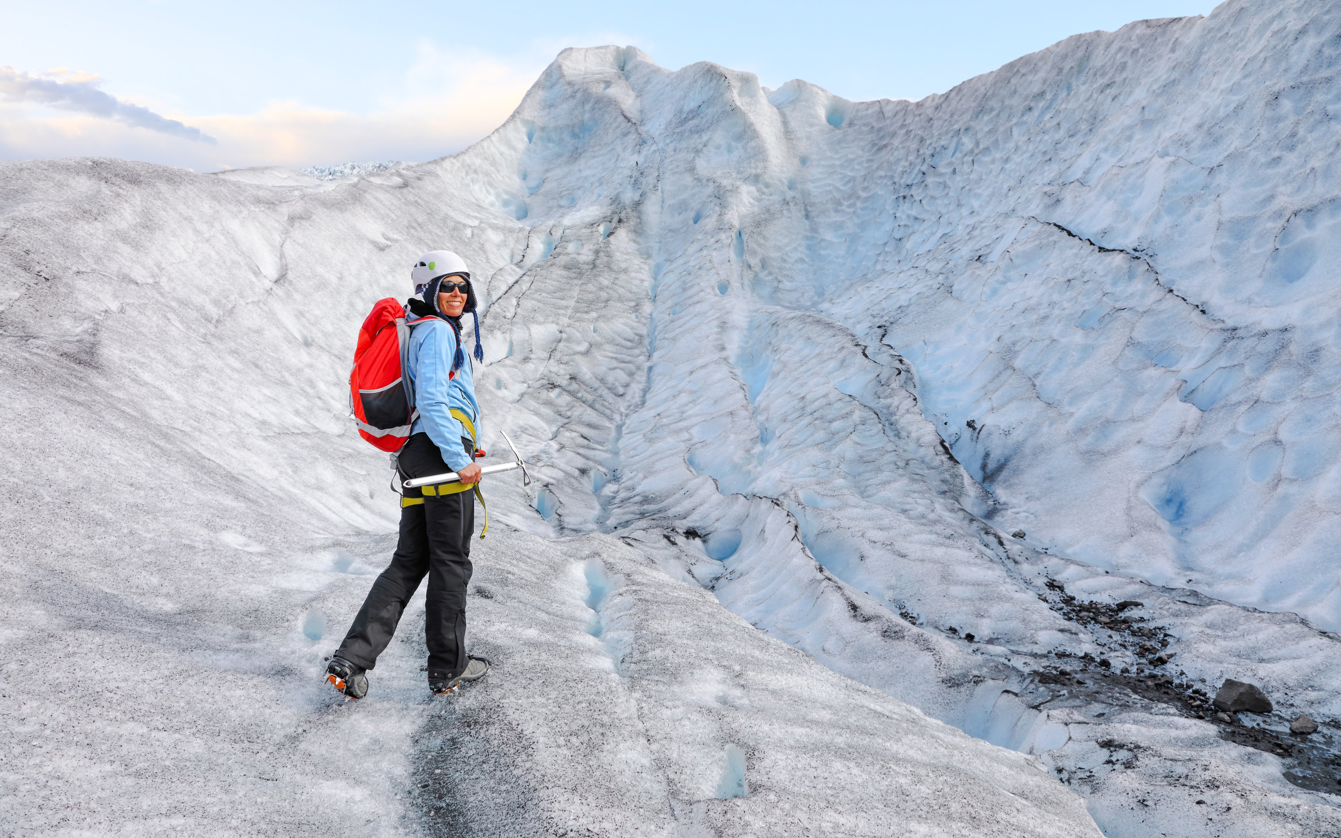 Person hiking on Falljokull glacier in Iceland with ice axe and backpack.