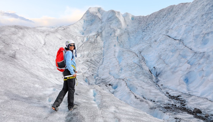Person hiking on Falljokull glacier in Iceland with ice axe and backpack.