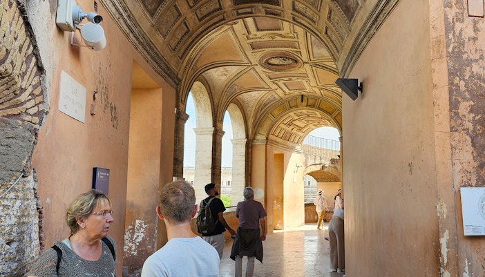 Visitors exploring interior of Castel Sant'Angelo, Rome, Italy, with ancient architecture and historical artifacts.