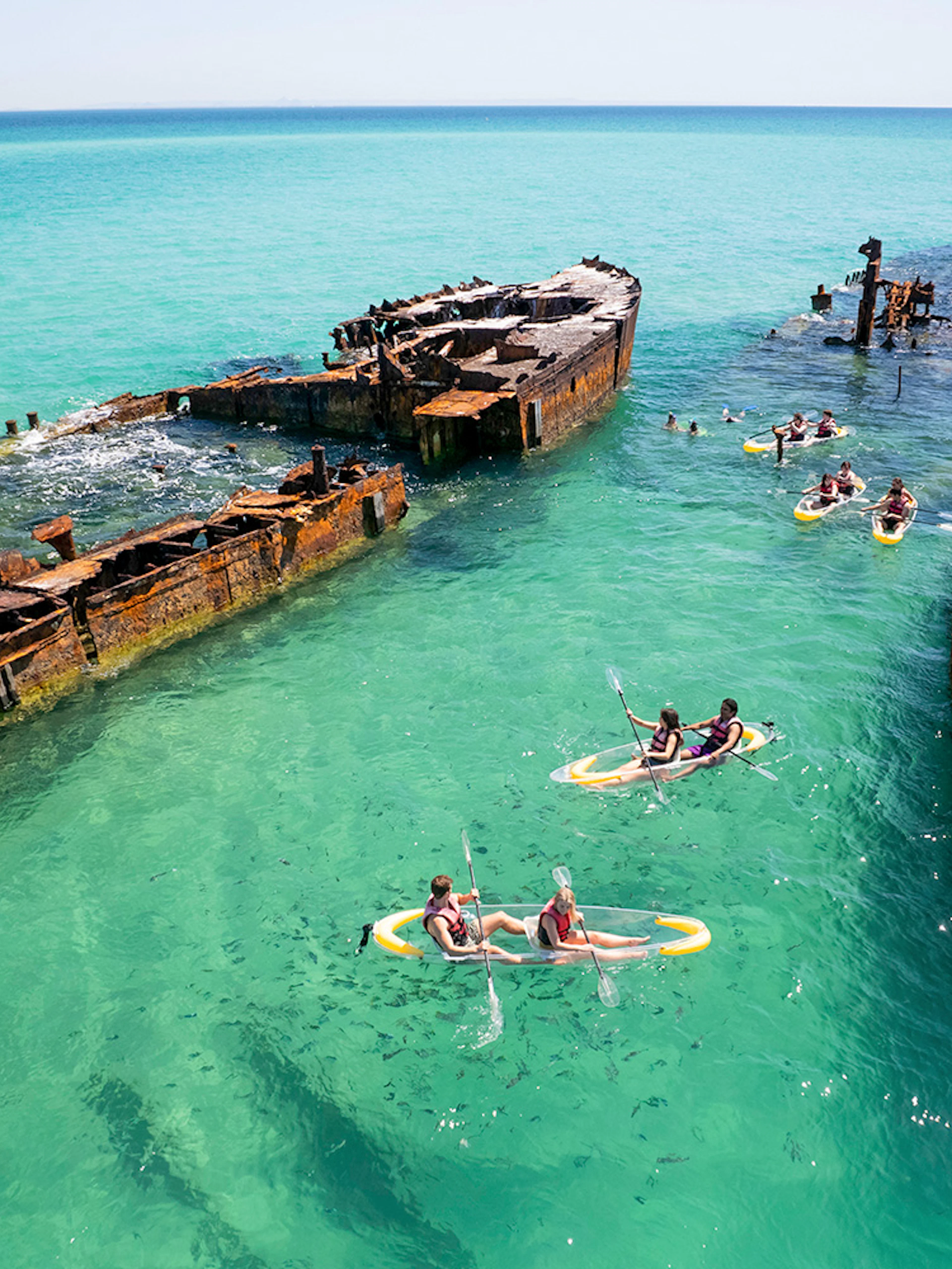 Kayakers exploring shipwrecks in turquoise waters at Moreton Island.