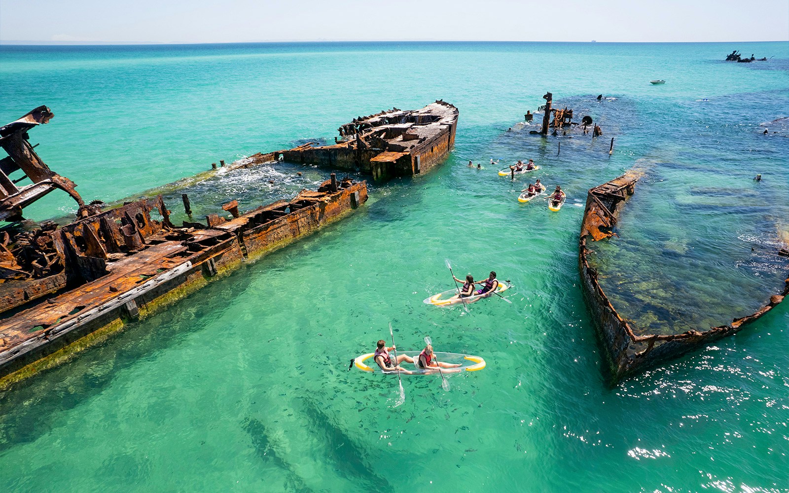 Kayakers exploring shipwrecks in turquoise waters at Moreton Island.