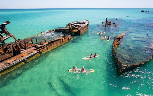 Kayakers exploring shipwrecks in turquoise waters at Moreton Island.