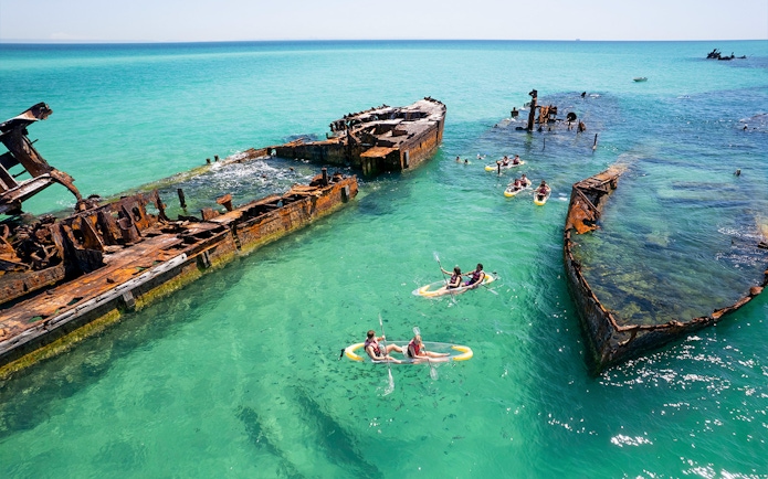 Kayakers exploring shipwrecks in turquoise waters at Moreton Island.
