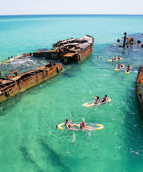 Kayakers exploring shipwrecks in turquoise waters at Moreton Island.