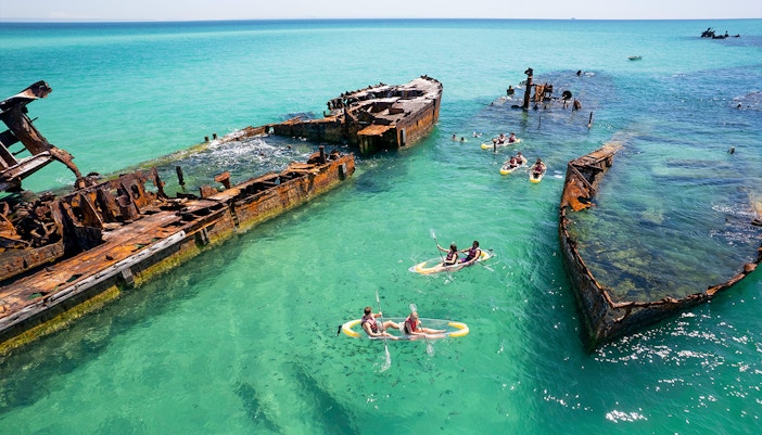 Kayakers exploring shipwrecks in turquoise waters at Moreton Island.