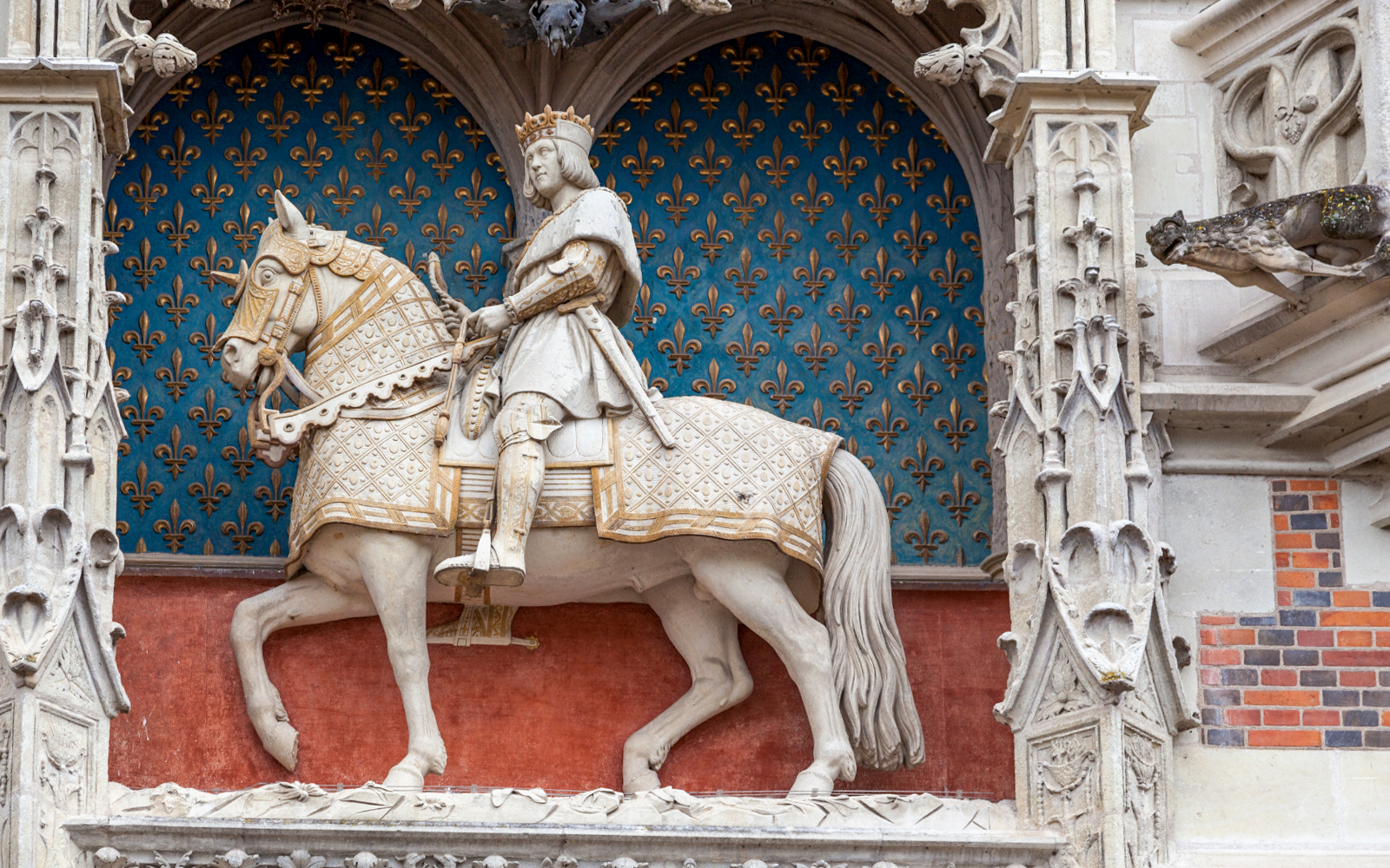Equestrian statue of a king on a horse with ornate armor, set against a fleur-de-lis backdrop.