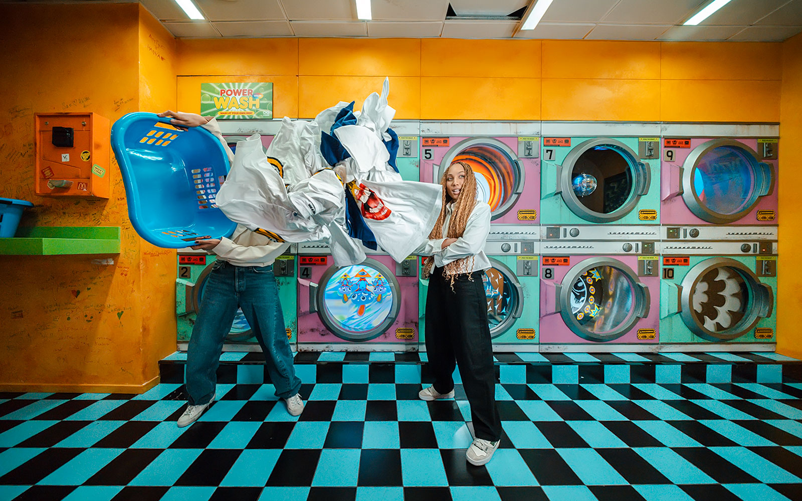 Tourist having fun in a colorful laundromat exhibit at House of Hype, Dubai.