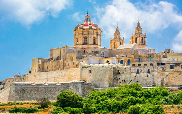 Mdina Cathedral and city walls under blue sky, Malta.