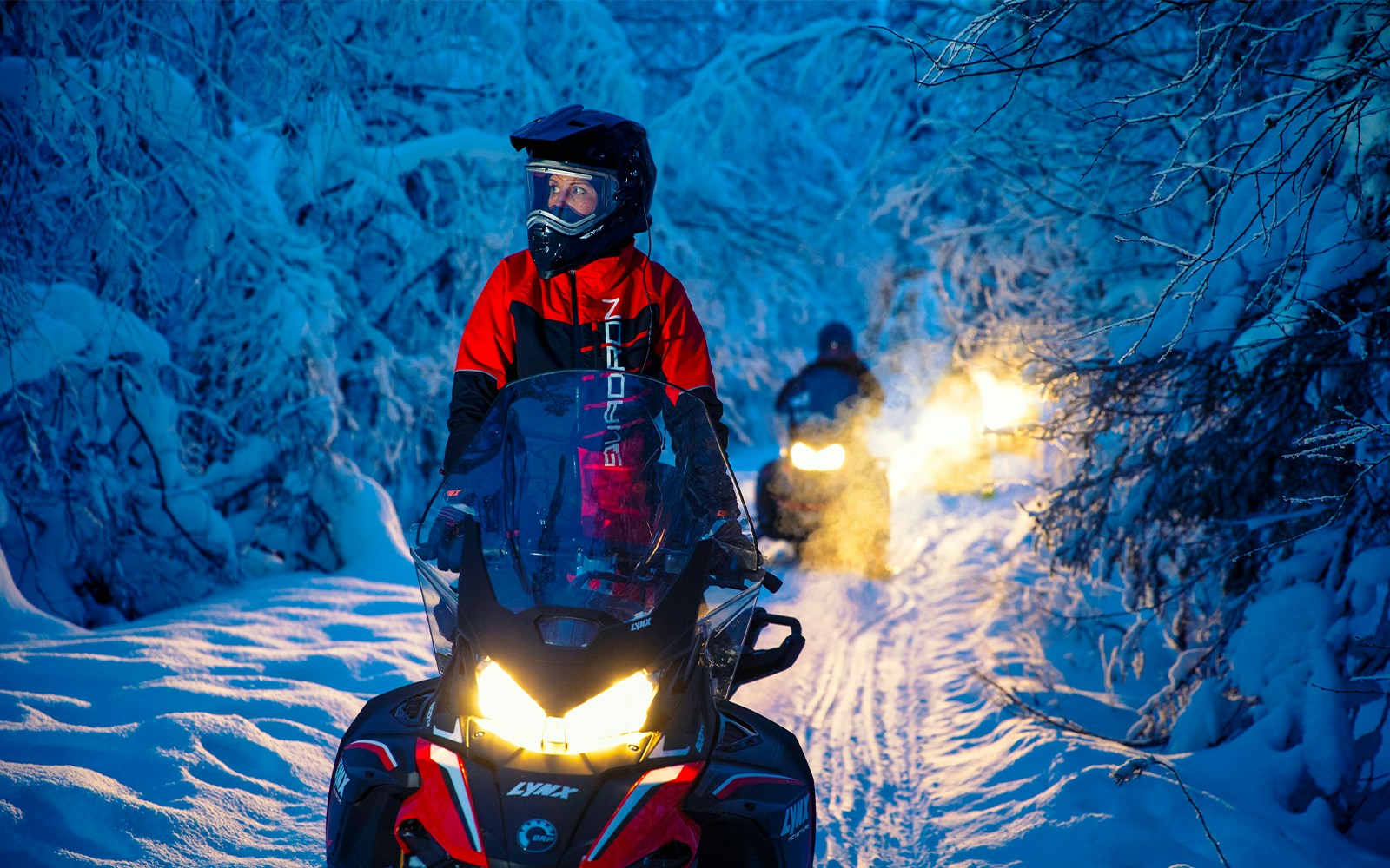 Snowmobiles on snowy terrain under Northern Lights in Rovaniemi, Finland.