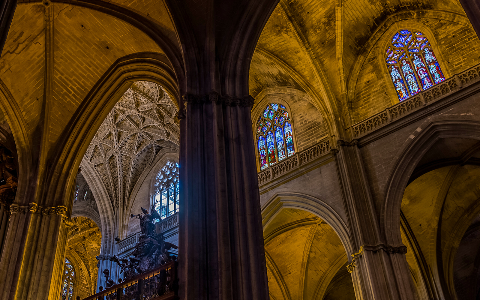 Seville Cathedral stained glass window depicting religious figures and intricate designs.