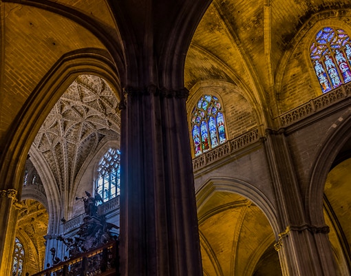 Seville Cathedral stained glass window depicting religious figures and intricate designs.