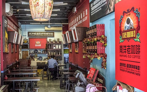 Singapore Chinatown coffee shop interior with traditional decor and visitor seated at a table.
