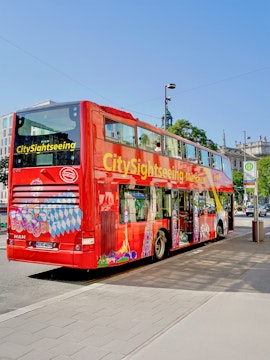 Red double-decker bus for city sightseeing in Munich, Germany, parked on a street.