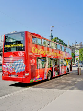 Red double-decker bus for city sightseeing in Munich, Germany, parked on a street.