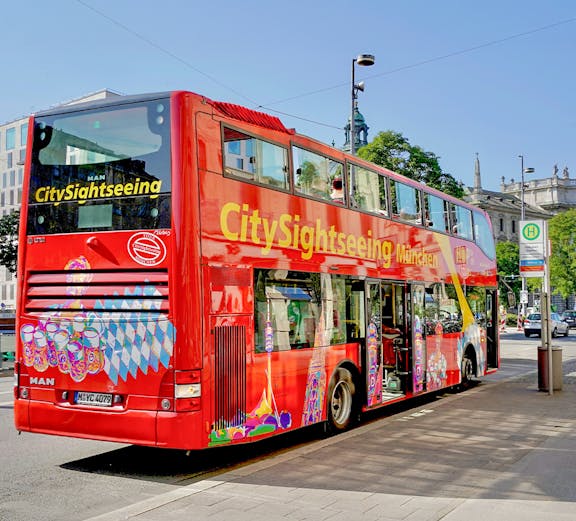 Red double-decker bus for city sightseeing in Munich, Germany, parked on a street.