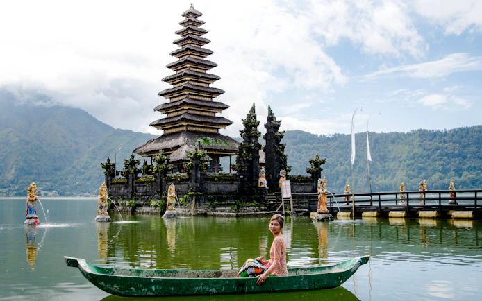 Pura Segara Ulun Danu Batur temple on Lake Batur, Bali, with a person in a boat.