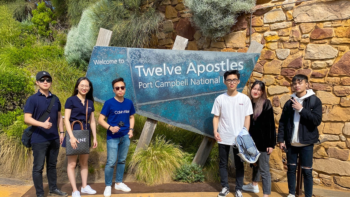 Twelve Apostles sign with people on Great Ocean Road, Melbourne.
