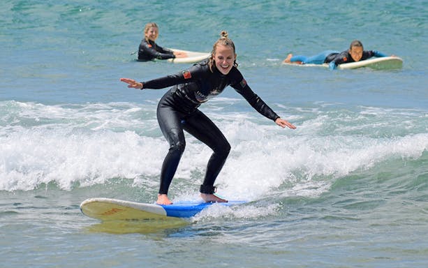 Group surf lesson participants riding waves in Lisbon.