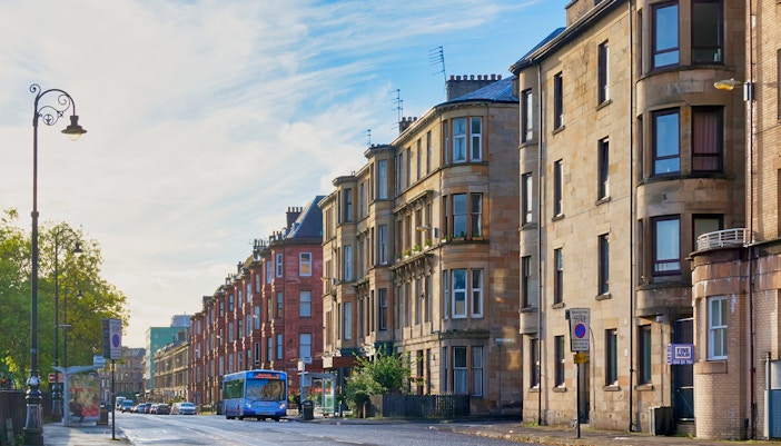 Sauchiehall Street in Glasgow with historic tenement buildings and a city bus.