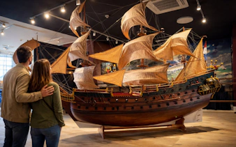 Couple admiring a large ship model at Miniature Museum, Amsterdam.