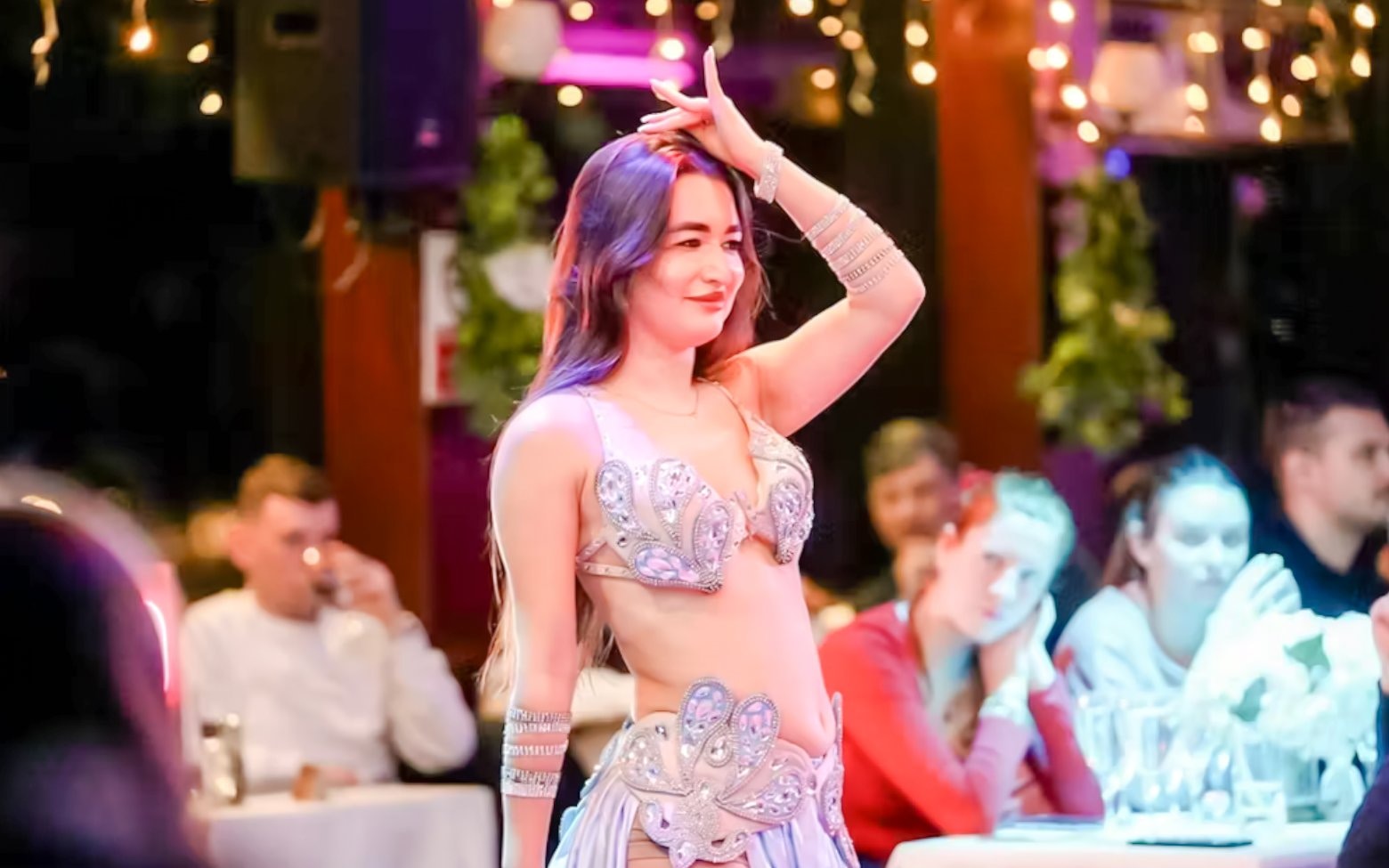 Belly dancer performing on a Bosphorus night cruise with an audience watching.