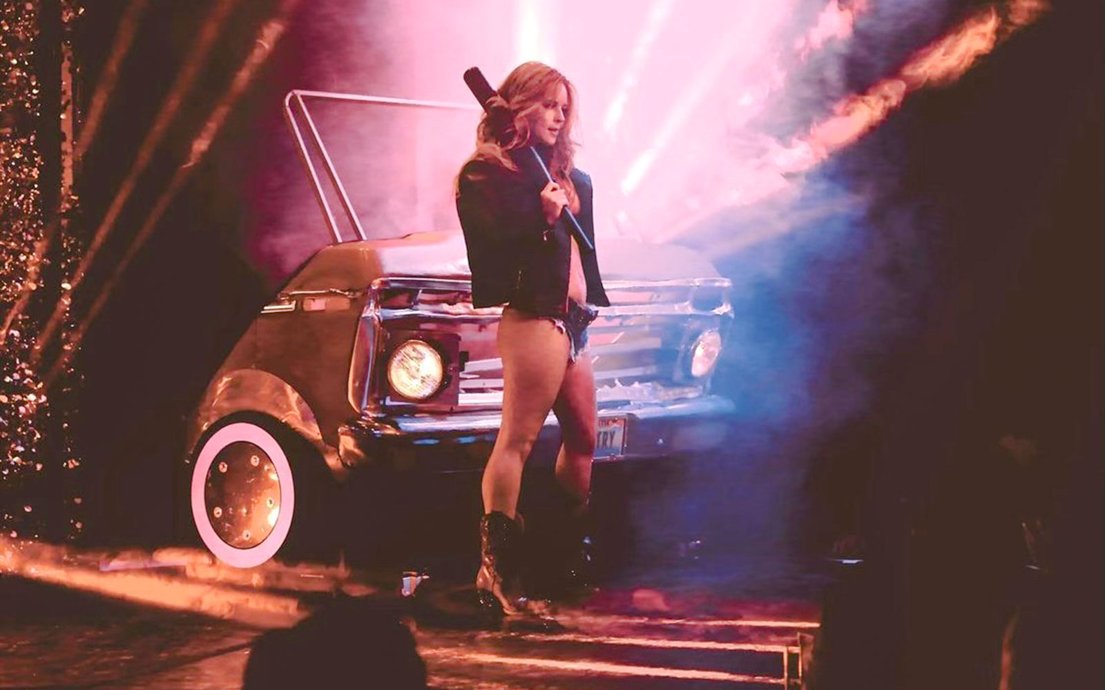 Performer on stage with vintage car backdrop during Vegas revue show.