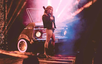 Performer on stage with vintage car backdrop during Vegas revue show.