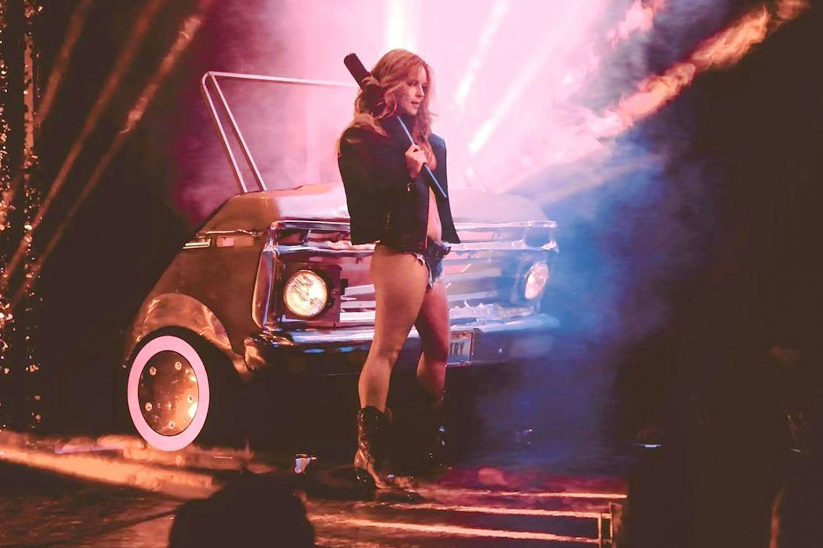 Performer on stage with vintage car backdrop during Vegas revue show.