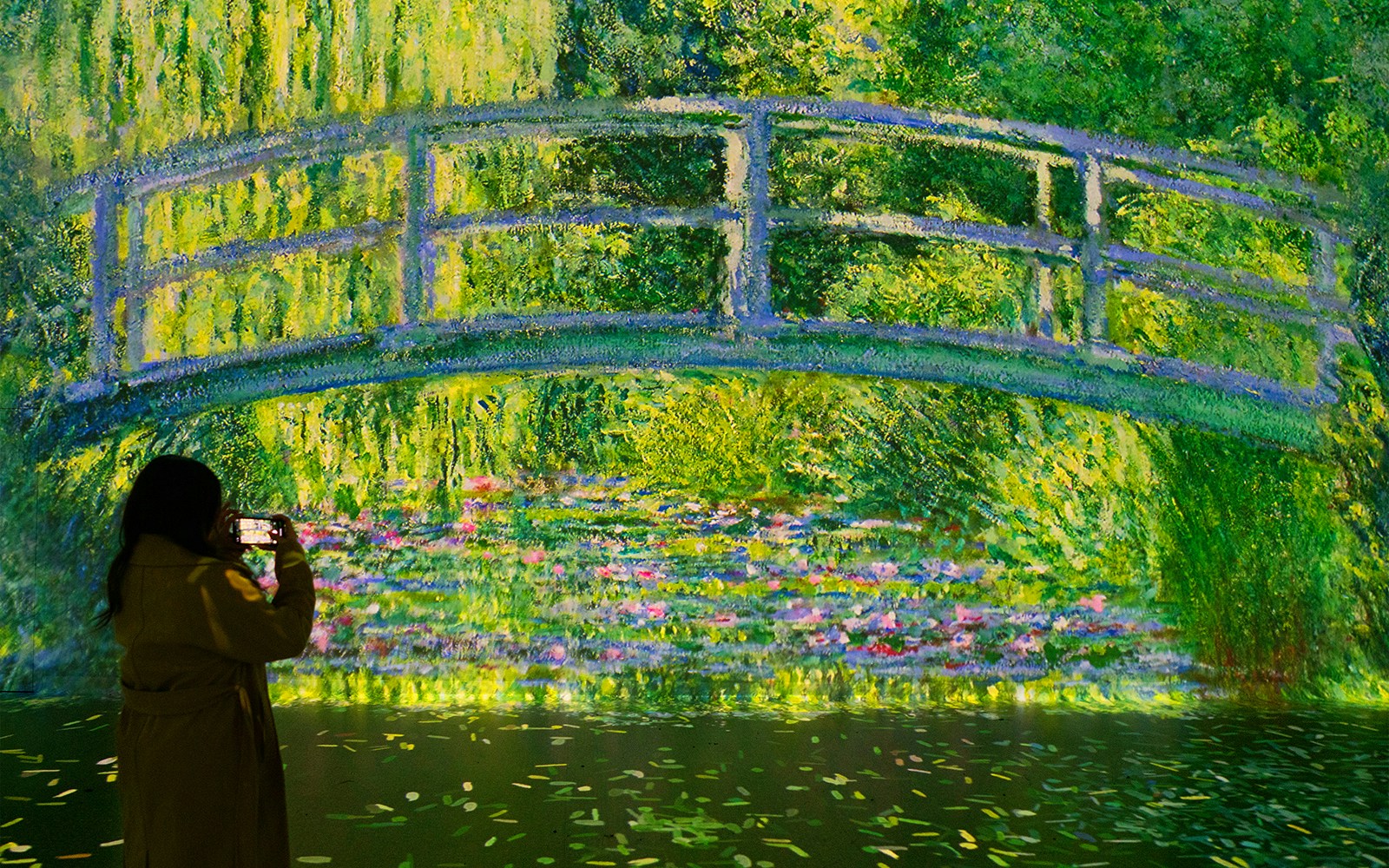 Visitor photographing Monet's Water Lilies projection at Frameless London exhibit.