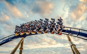 Roller coaster with riders at Busch Gardens against a cloudy sky.