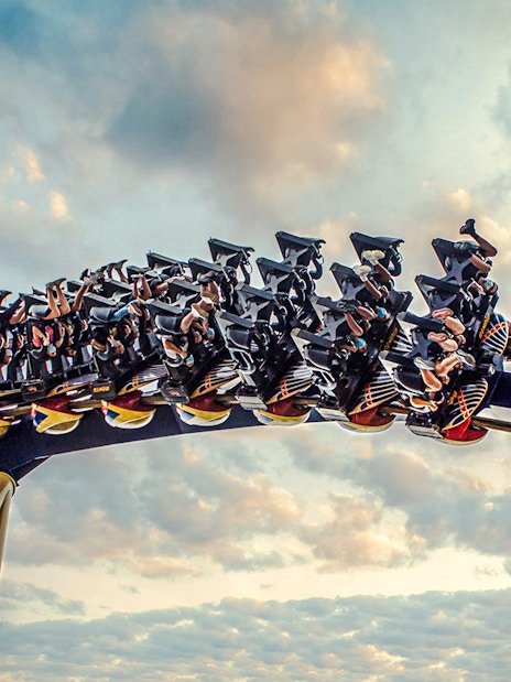 Roller coaster with riders at Busch Gardens against a cloudy sky.