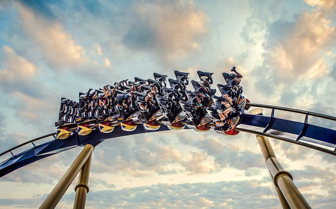 Roller coaster with riders at Busch Gardens against a cloudy sky.