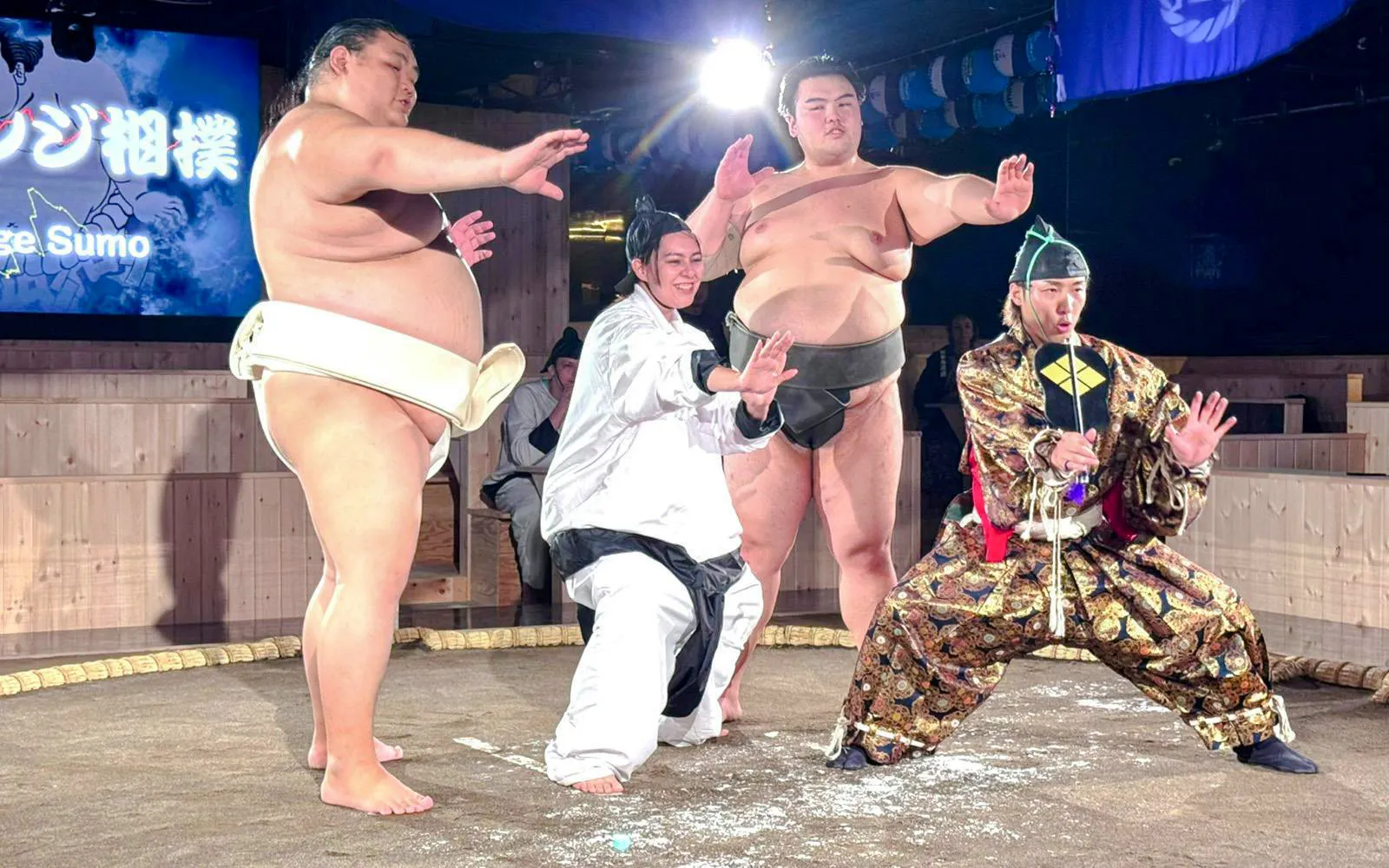 Sumo wrestlers and tourists posing at Authentic Sumo Experience in Tokyo.