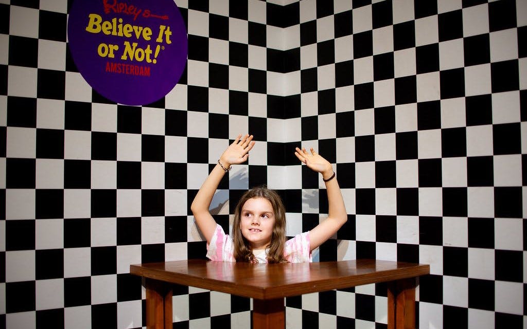 Child at Ripley's Believe It or Not! Amsterdam in optical illusion room with checkered walls.