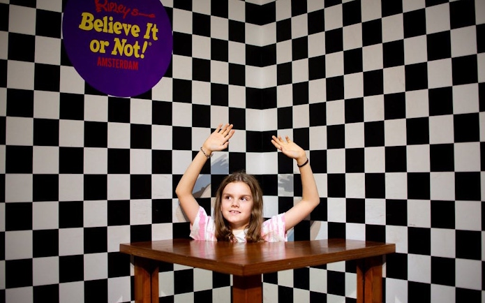 Child at Ripley's Believe It or Not! Amsterdam in optical illusion room with checkered walls.