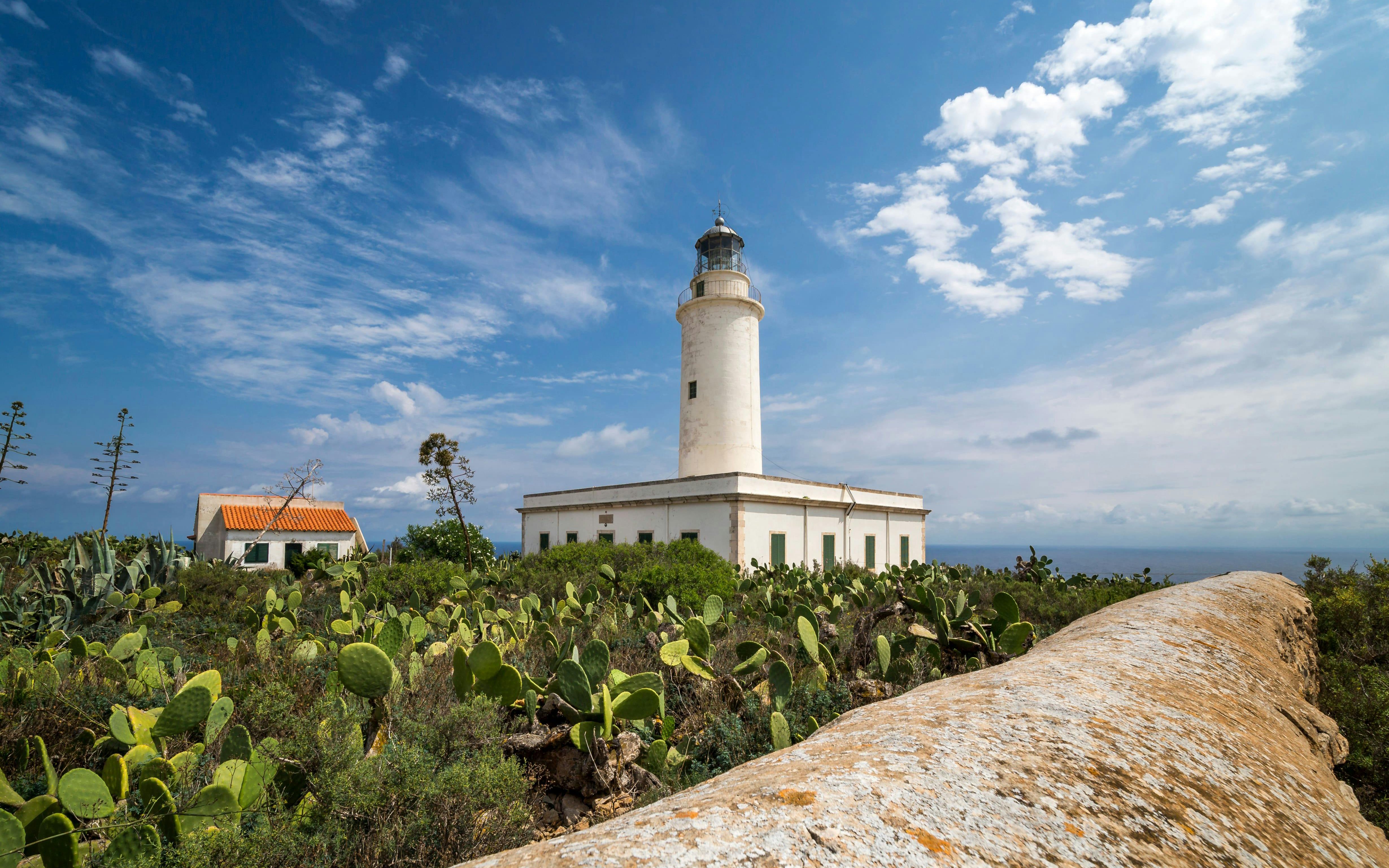 Far de la Mola lighthouse surrounded by greenery on Formentera's eastern edge, Spain.